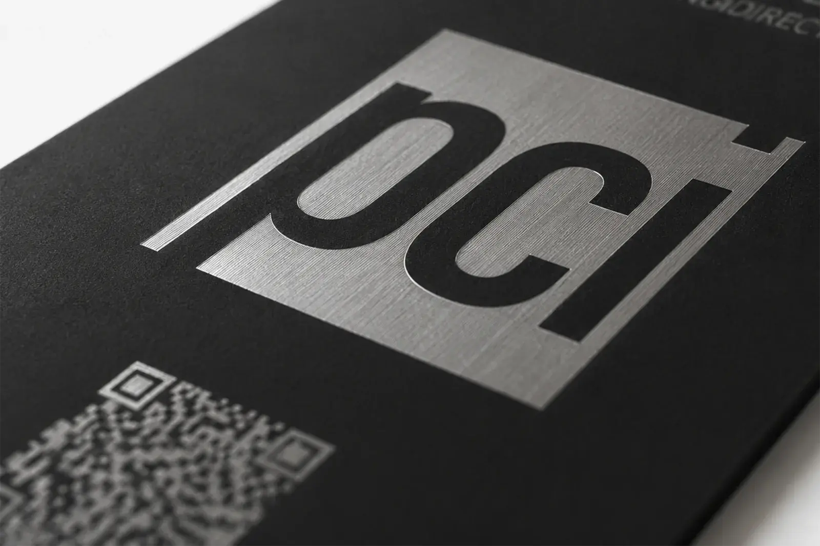 Macro detail of a company logo etched into brushed steel on a black metal card
