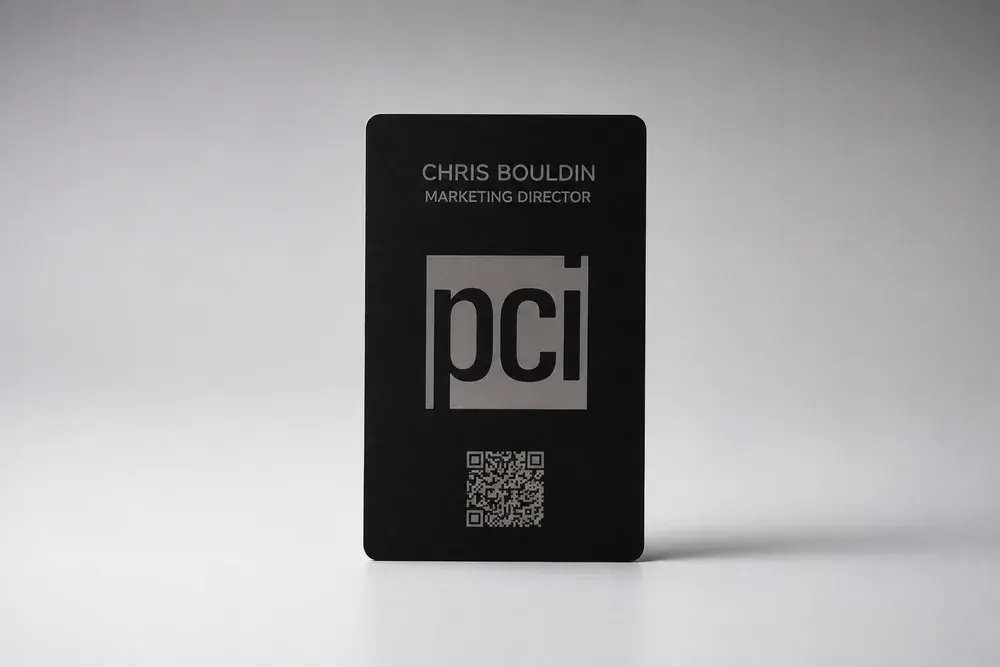 A portrait Bümpis metal card etched with a company logo, employee name and title